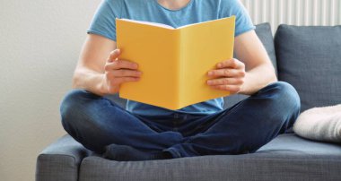adam kanepede bir kitap okuyor