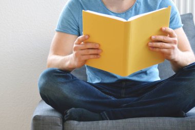 adam kanepede bir kitap okuyor