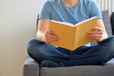adam kanepede bir kitap okuyor