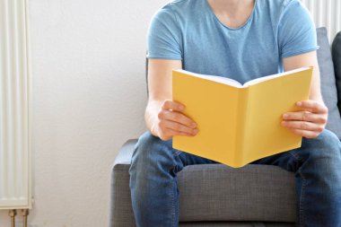 adam kanepede bir kitap okuyor