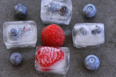 koyu bir arka plan üzerinde buz küpleri halinde dondurulmuş çilek 