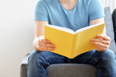 adam kanepede bir kitap okuyor