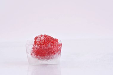 Beyaz arka planda buz küpü içinde Ahududu