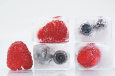 koyu bir arka plan üzerinde buz küpleri halinde dondurulmuş çilek 