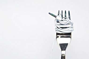Headphone cable wrapped on a fork against white background 