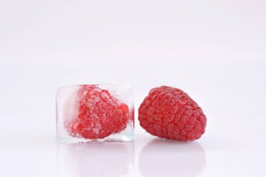 Beyaz arka planda buz küpü içinde Ahududu