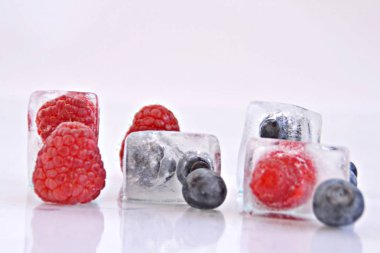 koyu bir arka plan üzerinde buz küpleri halinde dondurulmuş çilek 