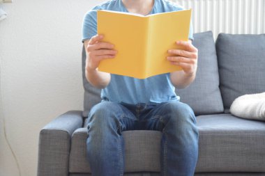 adam kanepede bir kitap okuyor