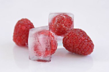 Beyaz arka planda buz küpleri içinde Ahududu