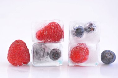 Beyaz arka planda buz küpü yaban mersini ve ahududu