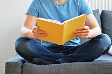 adam kanepede bir kitap okuyor