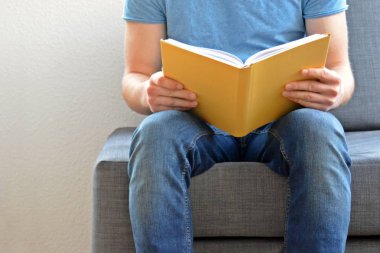 adam kanepede bir kitap okuyor