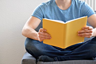 adam kanepede bir kitap okuyor