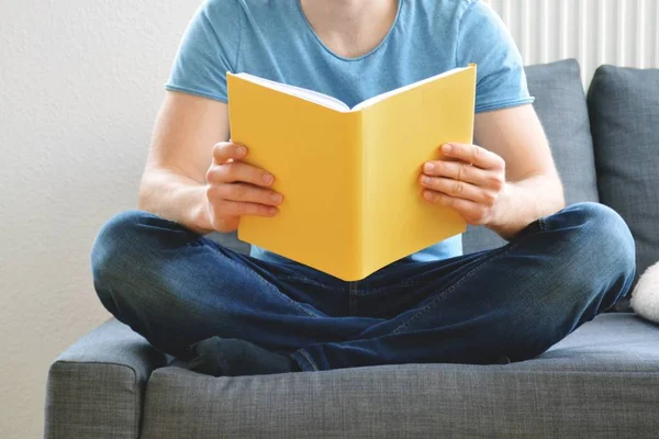 adam kanepede bir kitap okuyor