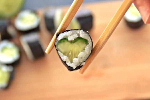 きゅうりときゅうりでハート型の寿司を食べる 寿司に恋する象徴としてクローズアップ — ストック写真