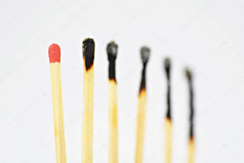 On a white, bright surface are many burned matches, only a single is intact and has a red head - concept for a competition from which only one person can emerge victorious