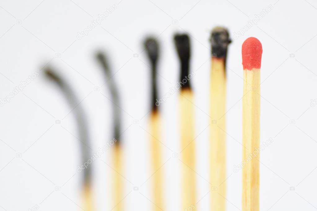 On a white, bright surface are many burned matches, only a single is intact and has a red head - concept for a competition from which only one person can emerge victorious