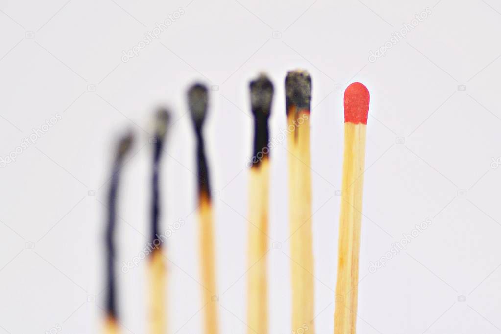 On a white, bright surface are many burned matches, only a single is intact and has a red head - concept for a competition from which only one person can emerge victorious