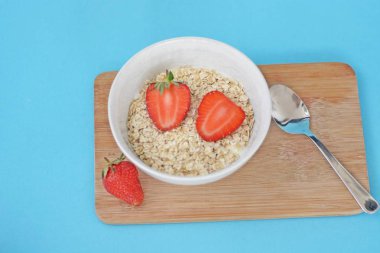 Sabahları sağlıklı bir kahvaltı olarak bir kase çilek ile yulaf ezmesi