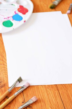 Bir renk paleti ve birçok fırça lar yanı sıra ahşap bir arka plan üzerinde fırça su renkleri ile bir kağıt levha