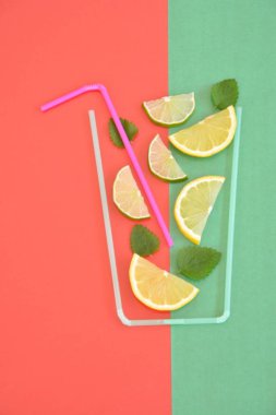 Yaratıcı düzeni çilek limonata malzemeler - limon, narenciye, buz renkli arka plan üzerinde kokteyl pipetleri ile yapılan cam düşen. Yaz içkileri. Minimal gıda konsepti. Seçici odaklama.