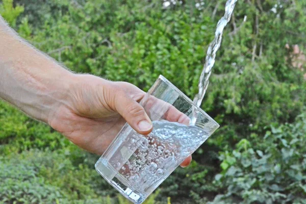 Água Fresca Limpa Flui Copo Frente Fundo Verão Verde Segurado — Fotografia de Stock