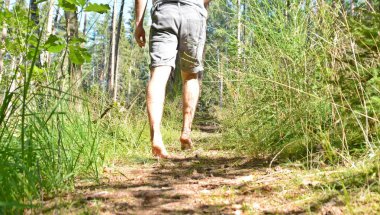 Ayaklarda yakın çekim - ormanda çakıl bir yol boyunca yürür ve yazlık sıcaklıklarda doğada rahatlatır