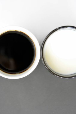Yarım siyah ve yarım beyaz arka plan önünde iki bardak, bir fincan kahve içerir, diğer süt ve her ikisi de bir kontrast creat, kahve fincanları ile yin ve yang için kavram