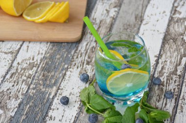 ahşap bir masada nane, narenciye ve yaban mersini ile yaz içkisi