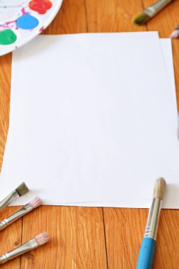 Bir renk paleti ve birçok fırça lar yanı sıra ahşap bir arka plan üzerinde fırça su renkleri ile bir kağıt levha