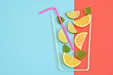 Yaratıcı düzeni çilek limonata malzemeler - limon, narenciye, buz renkli arka plan üzerinde kokteyl pipetleri ile yapılan cam düşen. Yaz içkileri. Minimal gıda konsepti. Seçici odaklama.