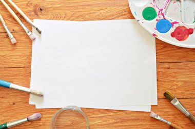 Bir renk paleti ve birçok fırça lar yanı sıra ahşap bir arka plan üzerinde fırça su renkleri ile bir kağıt levha