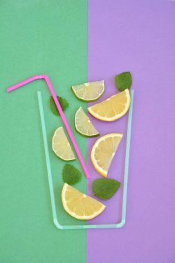 Yaratıcı düzeni çilek limonata malzemeler - limon, narenciye, buz renkli arka plan üzerinde kokteyl pipetleri ile yapılan cam düşen. Yaz içkileri. Minimal gıda konsepti. Seçici odaklama.