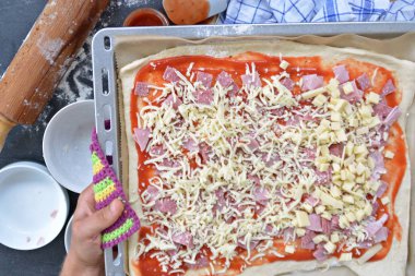 Yakın çekim-Man, jambon, salam ve peynir pişirme levha yanında malzemeler ile pizza hamur dolu bir pizza dolduruyor 