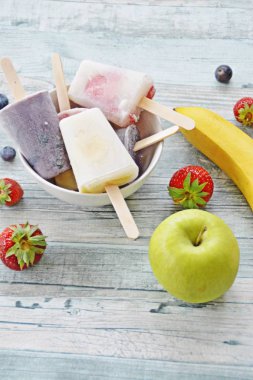 Bir ferahlık olarak yaz için mükemmel bir ahşap arka planda çilek, yaban mersini, elma ve muz ile ev yapımı dondurma