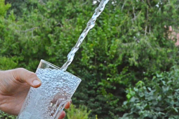 Água Fresca Limpa Flui Copo Frente Fundo Verão Verde Segurado — Fotografia de Stock