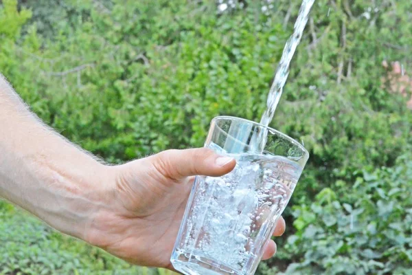 Água Fresca Limpa Flui Copo Frente Fundo Verão Verde Segurado — Fotografia de Stock