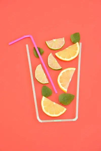 Creative layout strawberry lemonade ingredients - lemon, citrus, ice falling in glass made with cocktail straws on colorful background. Summer drinks. Minimal food concept. Selective focus.