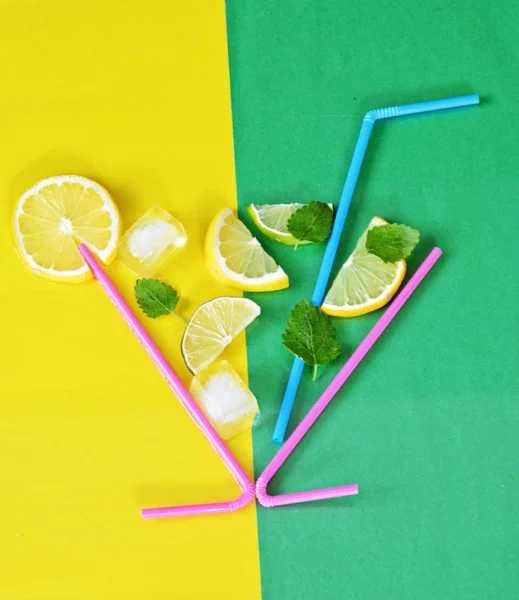 Concept for summer drink - Straws make up the glass in the lemons, limes, mint and ice floats against a colorful background - Abstract illustration of a summery refreshmentwith space for text