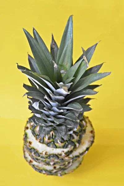 slices of a pineapple make up a whole pineapple in front of a solid background with space for text or objects