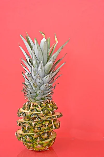 slices of a pineapple make up a whole pineapple in front of a solid background with space for text or objects