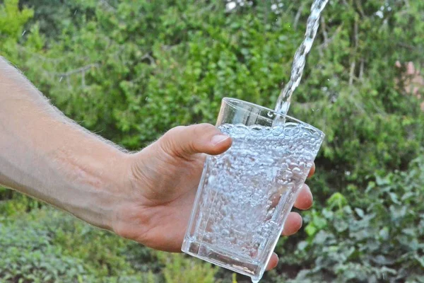 Água Fresca Limpa Flui Copo Frente Fundo Verão Verde Segurado — Fotografia de Stock