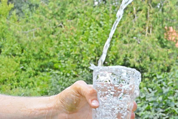 Água Fresca Limpa Flui Copo Frente Fundo Verão Verde Segurado — Fotografia de Stock