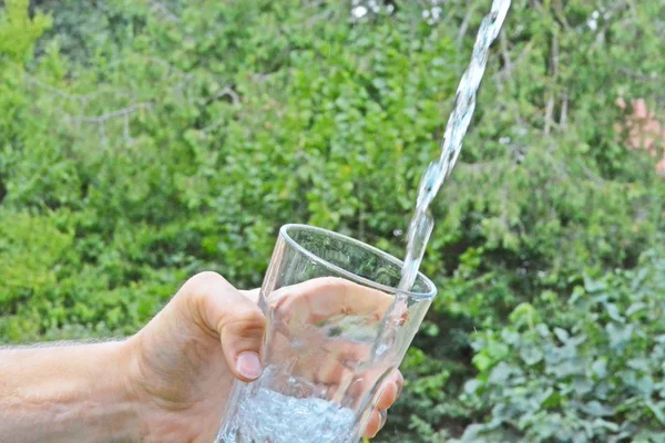 Água Fresca Limpa Flui Copo Frente Fundo Verão Verde Segurado — Fotografia de Stock