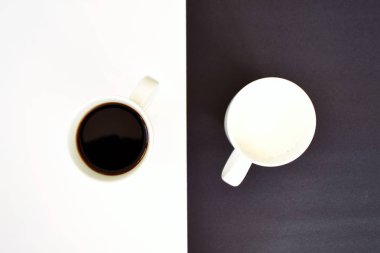 Yarım siyah ve yarım beyaz arka plan önünde iki bardak, bir fincan kahve içerir, diğer süt ve her ikisi de bir kontrast creat, kahve fincanları ile yin ve yang için kavram