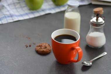 Elma, süt, şeker ve bisküvi ile bir masada bir portakal fincan Kahve 