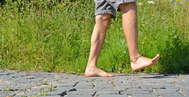 Arka planda bitkiler ile yaz aylarında parke taşı üzerinde yalınayak Yürüyüş 