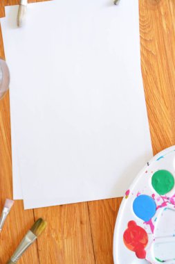 Bir renk paleti ve birçok fırça lar yanı sıra ahşap bir arka plan üzerinde fırça su renkleri ile bir kağıt levha