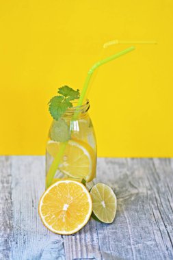 Elinizde buz, limon, limon ve nane dolu bir bardak tutma - metin veya diğer öğeler için alan ile renkli bir arka plan üzerinde ruh için mükemmel bir maç 