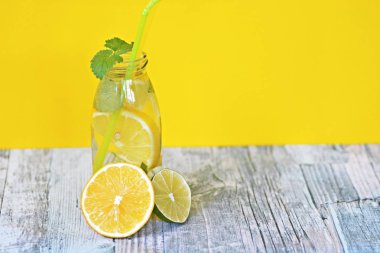 Elinizde buz, limon, limon ve nane dolu bir bardak tutma - metin veya diğer öğeler için alan ile renkli bir arka plan üzerinde ruh için mükemmel bir maç 